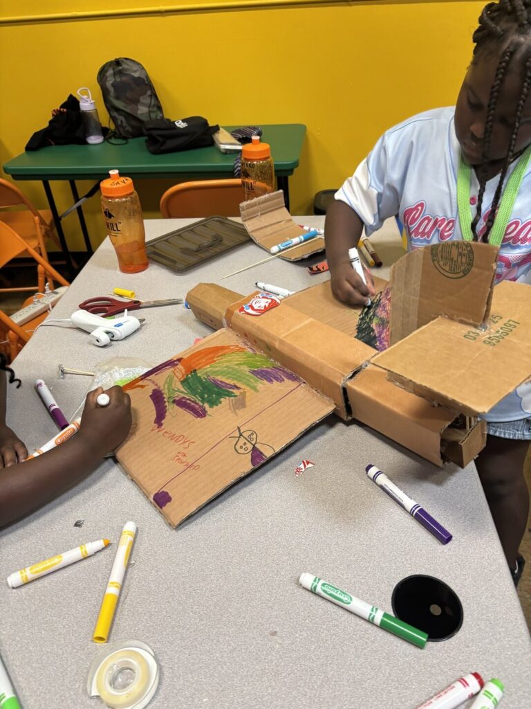 Student decorating a cardboard build with markers at a STEMCAT workshop