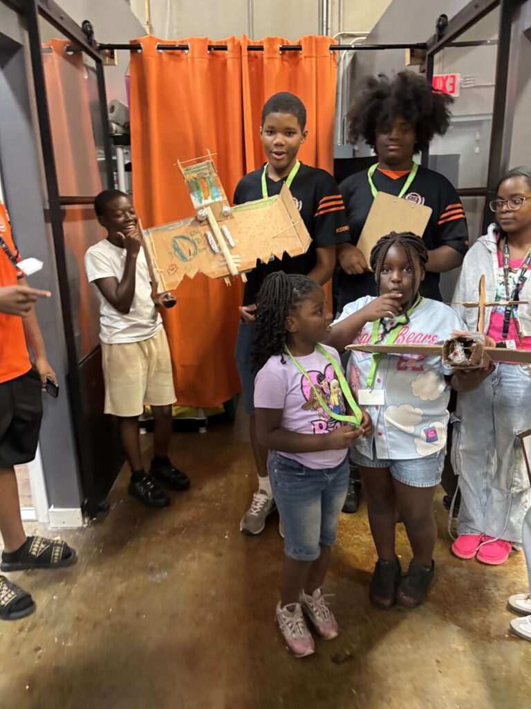 Young students holding up the projects they built