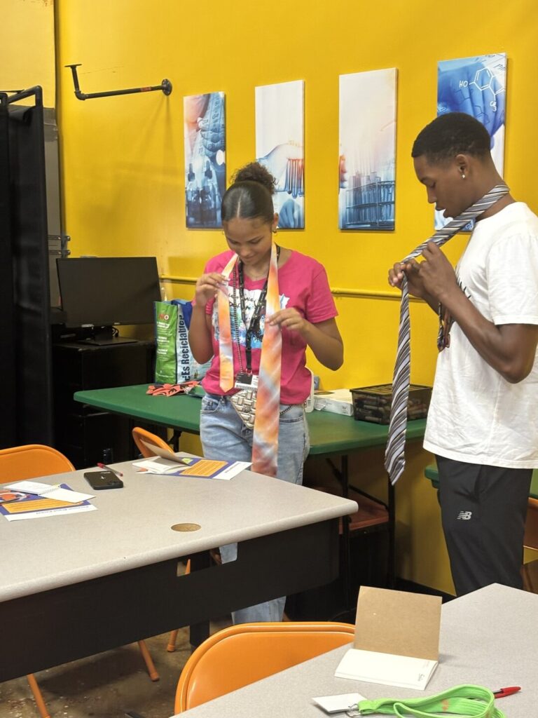 Teen students practicing how to tie a tie at a career-readiness session