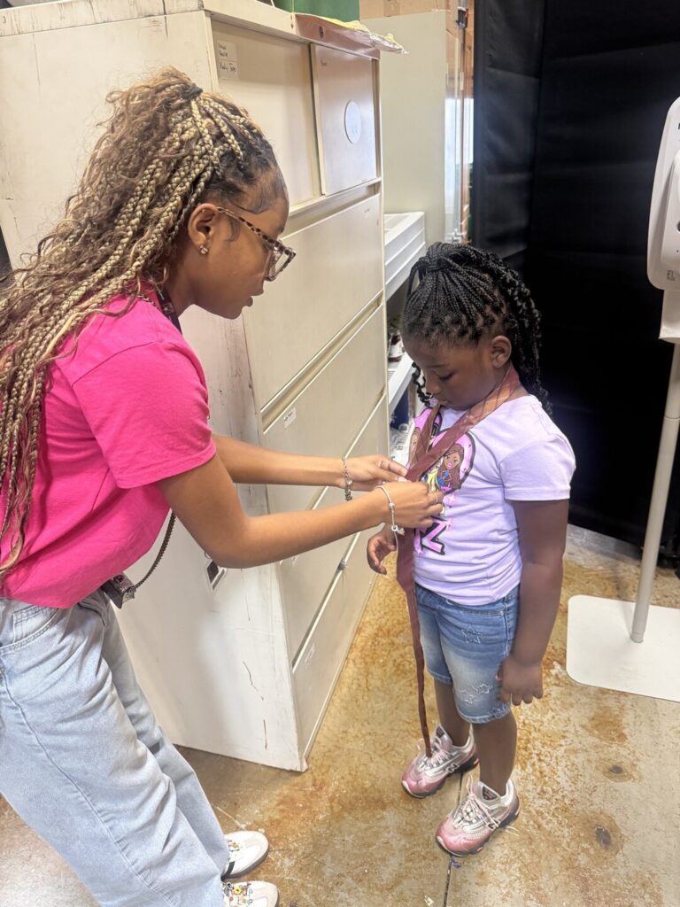 Older student helping a younger student with her tie