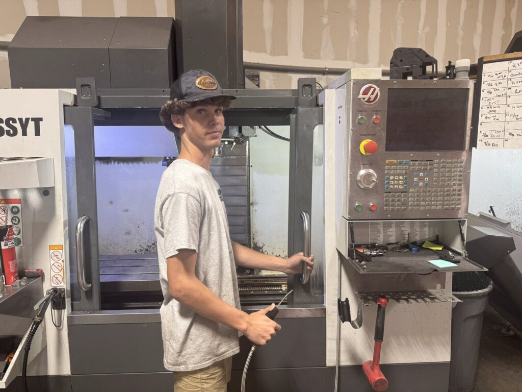 Student operating a CNC machine in a manufacturing shop