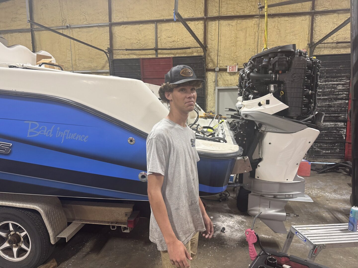 Student in a marine service shop beside a boat