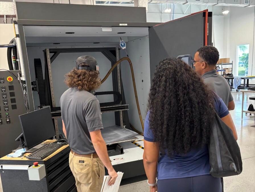 STEMCAT participants learning on an industrial 3D printer at employer partner ADDMAN